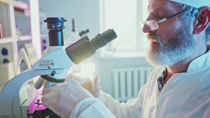 Wall Mural - professional scientist wearing white lab coat and glasses carefully adjusting microscope while analy