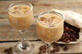Coffee cream liqueur in glasses and beans on table, closeup