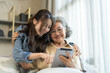 © Art_Photo - Asian senior mother and daughter smiling and talking using tablet browsing social media, shopping online, watching movies or series, enjoying entertainment digital connection and bonding at home