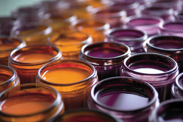 Poster - Close-up of orange and purple paint in glass jars, arranged in rows.  Showcase of vibrant color gradients, ideal for design or artistic concepts