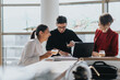 © qunica.com - Three business colleagues enjoy a relaxed meeting in an office kitchen. They are discussing work while sharing a drink, fostering teamwork and collaboration in a modern work environment.