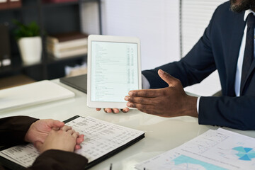 Poster - Close-up of businessman discussing financial report on tablet pc with his colleague at table