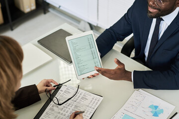 Poster - High angle view of colleagues making analysis of financial report while sitting at table at meeting