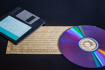 Aufkleber - An old punch card, computer floppy disk, and compact disc on a dark background, showcasing outdated technology, 20th-century technology, early computer data, and an old archive.