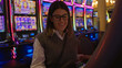 © Krakenimages.com - Woman enjoys playing slot machines indoors at a vibrant las vegas casino, surrounded by colorful neon lights, creating a lively and thrilling atmosphere.