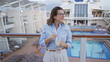 © Krakenimages.com - Woman enjoying cruise outdoors on dock with pool while holding drink in hand looking content and relaxed amidst blue skies and modern ship design.