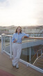 © Krakenimages.com - Woman enjoying drink on cruise ship deck with cityscape view at dusk reflects relaxation and travel vibes outdoors.
