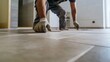 © Mcgui - Construction worker placing tiles on a bathroom floor in a new home. Featuring care and detail