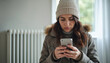 © Pete - Stressed brunette woman in winter coat hat calls to service to repair broken heater radiator. Cold home concept, emergency, wintertime problem, cold weather house situation, need repair.