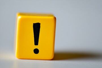 Poster - A yellow cube with a black exclamation point on it sitting on a white surface in a studio setting