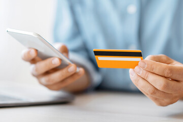 Poster - Unrecognizable man using smartphone and credit card in office, paying bills online, using mobile application for money trasfers, closeup
