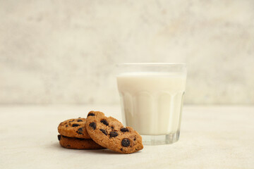 Wall Mural - sweet cookies with chocolate chips and glass of milk on white background