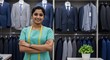 © rdkcho - Confident young Indian female tailor standing with arms crossed in her tailor shop, surrounded by men's suits.