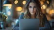 © tuiphotoengineer - Attractive young woman with brown hair and eyes working intently on her laptop computer in a warm cozy coffee shop setting  The blurred background creates a comfortable