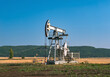 © Evgenii Bakhchev - A large oil pump jack operates in an open field, extracting crude oil