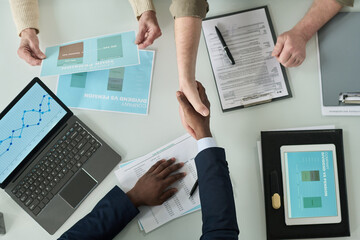 Poster - Top view of financial agent shaking hands with senior people while they sitting at table and applying pension