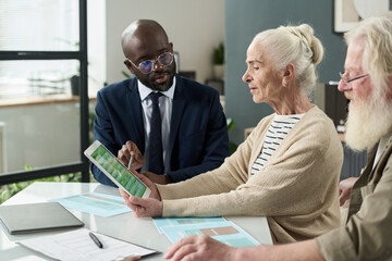 Poster - Senior woman filling online form on tablet pc together with financial agent in office