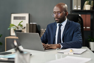 Poster - Serious businessman concentrating on his online work on laptop while sitting at workplace in office