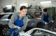 © JackF - At service station, worker is engaged in straightening, eliminating deformations of car body. Auto mechanic at work. Girl auto mechanic polishes body parts by car buffer polisher machine tool