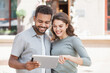 © kite_rin - Beautiful happy young couple using digital tablet outdoors. Joyful smiling woman and man looking at tablet in a city. Love, travel, tourism, students lifestyle concept