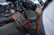 © zinkevych - Repair specialist measuring battery charge with voltmeter for diagnostic service