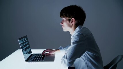 Aufkleber - Focused professional developer working late at night, typing source code on laptop while sitting at luminous table in dimly lit workspace, concentrating on programming task