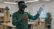 © Milan - Young African American professional man using VR headset in modern office and showing thumbs up. Black man in green shirt gesturing with virtual reality interface. Augmented reality concept