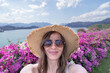 © Vladimir Razgulyaev - Portrait of a female traveler in sunglasses and a straw hat taking selfies against the backdrop of Thailand's nature, Cheo Lan Lake in Khao Sok Park. Tourism and solo travel