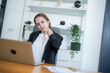 © Hip.hub - Woman experiencing neck pain while working at a desk in a modern office space during the afternoon