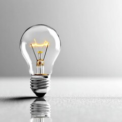 Aufkleber - Illuminated Idea: A Clear Glass Light Bulb Glowing Brightly, Reflecting on a Clean White Surface with Subtle Grayscale Background.
