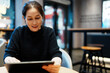 © zhouyilu - Engaging in Digital Learning: A Young Woman Interacting with a Tablet in a Modern Caf�