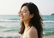 © Ozz - Joyful young woman smiles with eyes closed by the ocean, enjoying the sun and breeze.