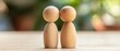 © Fernando - Two wooden figures standing together on a table, representing couple, family, relationship, unity, love, support, and connection in a blurred nature background