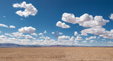 clouds over the field billowing fluffy cumulus desert sand dirt desolate isolated blue sky
