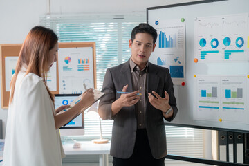 Fototapete - Asian businesspeople discussing and analyzing charts on whiteboard during a meeting