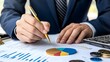 © Saroch - A person in a suit analyzes financial data with a pen on a document featuring graphs and a pie chart, alongside coins and a calculator.