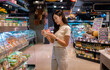 © Parichat - Young woman checking nutrition facts of packaged food in supermarket refrigerator shelves