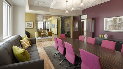Aufkleber - Modern office interior showcasing long conference table with pink chairs, gray sofa with pillows, glass-walled meeting area in background representing corporate workspace efficiency and stylish design