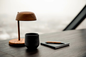 Poster - Stylish desk setup with coffee mug, notebook, and lamp by panoramic city view