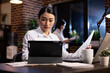 © DC Studio - Dedicated female professional working late in corporate office, reviewing business reports on a tablet. Asian manager surrounded with digital devices on her desk, focused on project planning at night.