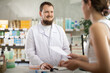 © JackF - Young man pharmacist looking for prescription on computer to young woman buyer in pharmacy