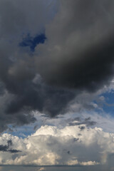 Wall Mural - Epic Dramatic storm dark grey cumulus rain clouds against blue sky background texture, thunderstorm