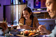 © Marko Geber - Smiling young woman checking smartphone while eating sushi with friends
