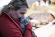 © Cavan Images - Woman cuddles blue-eyed kitten outdoors in soft natural light
