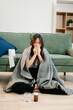 © Nuttapong punna - Young Asian woman suffering from flu symptoms, covered with a blanket on a sofa. Concept of illness, healthcare,