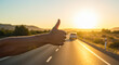 © Hanna - Hitchhiker signaling for a ride during sunset on a quiet road