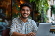 © Lamaba - A young man exudes an air of modern work with a warm, inviting smile, as he works outdoors. Sunlight casts a gentle glow upon his face and open laptop, creating a picture of productive work.