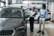 © standret - Looking at black vehicle. Car seller is assisting client in the automobile salon