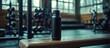© Almahyra - Black water bottle rests on gym bench; weights blur