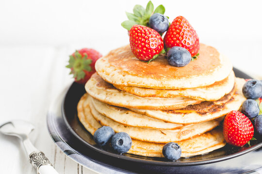 Close-up of a Stack of healthy homemade pancakes with maple syrup, fresh strawberries and blueberries
